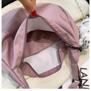 Detail of mauve nylon crescent bag showing spacious interior with white lining and plush charm