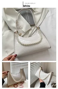 Detail view of white crocodile pattern underarm bag with decorative pearl strap
