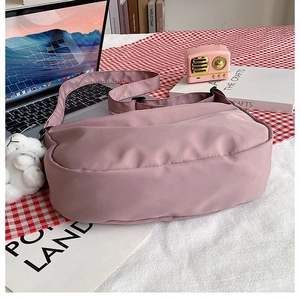 Detailed view of pink nylon crescent bag with cute bear charm on checkered tablecloth