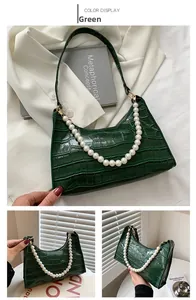 Close-up of green crocodile texture hobo bag with elegant large pearl handle detail