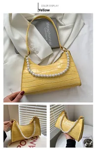 Detail of yellow crocodile pattern hobo bag with large pearl strap and sleek finish