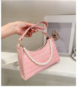 Close-up of pink faux crocodile skin texture and white pearl chain detail on hobo bag
