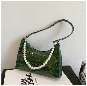Detail of dark green crocodile texture on hobo bag with white pearl strap accents