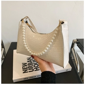Detail of white crocodile embossed leather handbag with large pearl strap and gold zipper