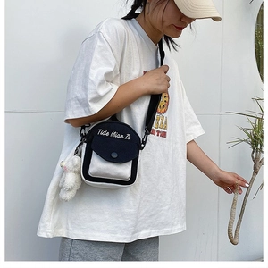 Detail of canvas crossbody bag with color block design and plush bear keychain accessory