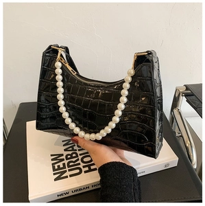 Detail of crocodile embossed leather texture and pearl handle on black shoulder bag