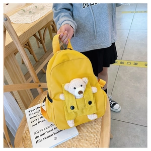 Close-up of bright yellow canvas kid's backpack featuring a 3D plush bear ornament