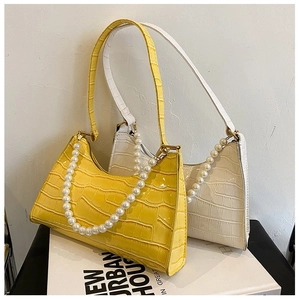 Detail showing faux crocodile leather texture and large pearl chain on the shoulder bags