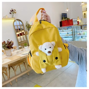 Detail of yellow canvas kids backpack with a cute plush bear in the corduroy pocket