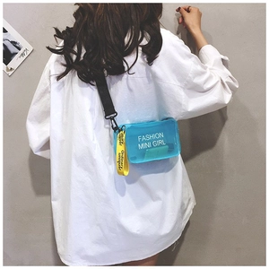 Dettaglio della borsa a sella trasparente blu con scritte moda e tracolla gialla