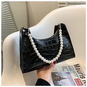 Close-up of black crocodile embossed shoulder bag featuring a white pearl handle