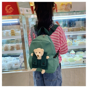Detail eines grünen Kinderrucksacks mit süßem Plüschbären in der Kordtasche aus Segeltuch