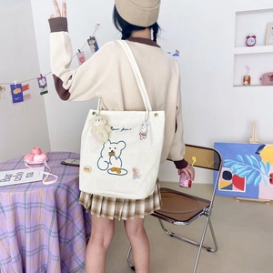 Gros plan du sac cabas en velours côtelé blanc avec broderie ours et accessoires