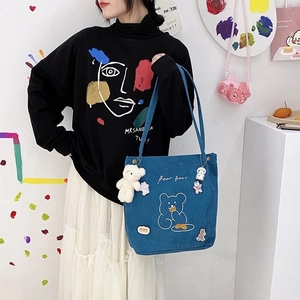 Détail du sac cabas en velours bleu avec broderie ours et badges cartoon