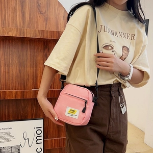 Dettaglio di una borsa a tracolla in nylon rosa con cinturino regolabile e logo