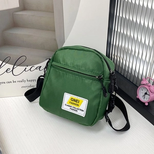Dettaglio della piccola borsa a tracolla in nylon verde con etichetta e cinturino