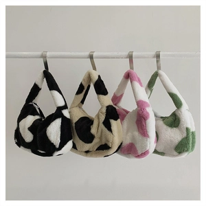Detailed view of plush faux fur tote bags in four cow print colors hanging on a rack