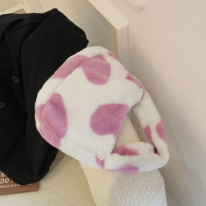 Close-up of pink cow print faux fur tote bag showing soft plush texture on a sofa