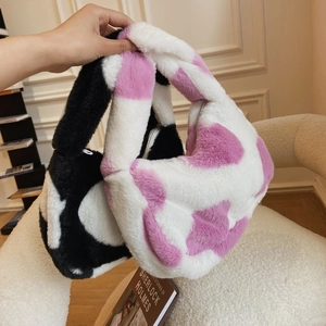 Detail of plush faux fur tote bags in cow print and pink heart patterns with top handles