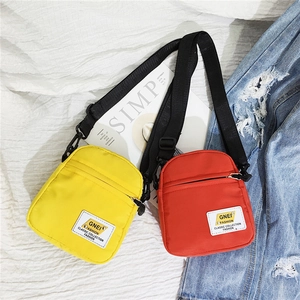 Mini borse a tracolla in nylon rosso e giallo con cinghie regolabili su sfondo alla moda