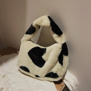 Detail of soft faux fur plush tote bag featuring black and white cow print texture