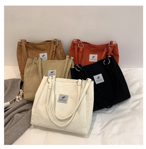 Detailed pile of colorful corduroy tote bags in brown orange beige and black colors