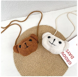 Détail de sacs bandoulière en peluche forme d'ours sur un tapis de paille tissé
