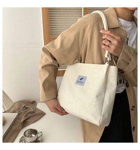 Detail of white corduroy tote bag with blue woven label and silver metal ring hardware