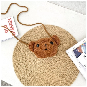 Vue de dessus d'un sac à bandoulière ours en peluche marron sur un tapis de paille doux