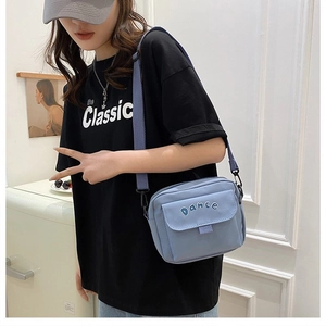 Detail of light blue canvas crossbody bag showing Dance letter design and strap