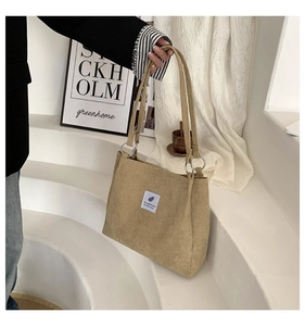 Close-up of beige corduroy tote bag featuring square woven label and silver metal ring links