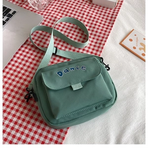 Detail of mint green canvas crossbody bag featuring Dance embroidery and adjustable strap