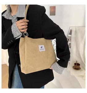 Detail of khaki corduroy tote bag with silver ring connector and minimalist logo patch