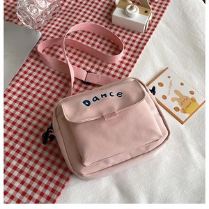 Detail of pink canvas crossbody bag with blue Dance print and adjustable strap