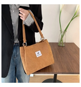 Close-up of brown corduroy tote bag with vintage feather label and silver metal rings