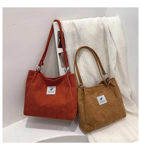Detail of corduroy tote bags in orange and brown with vertical textures and fabric labels