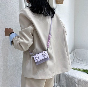 Detail of lavender patent leather crossbody bag with chain strap and double buckles
