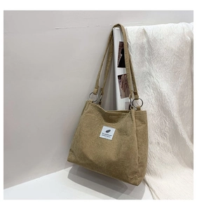 Detail of khaki corduroy tote bag showing vertical texture and white graphic patch