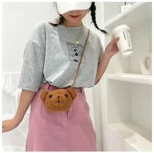 Sac bandoulière en peluche marron en forme d'ours porté par un modèle dans un décor épuré