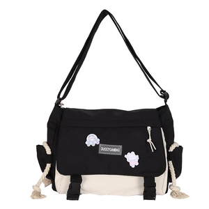 Black and white canvas messenger bag with cartoon badges and adjustable strap