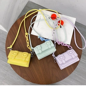 Three candy-colored crossbody bags in yellow, green, and purple with plastic chain straps