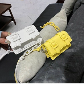 Detail of mini flap crossbody bag with chunky plastic chain handle in white and yellow