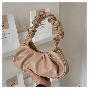 Detailed view of the gathered pleats and glossy finish on the beige baguette underarm bag