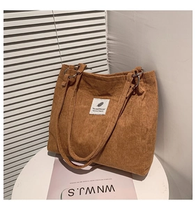 Detail of brown corduroy tote bag with vintage metal ring handle and decorative cloth label