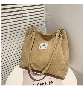 Detail of khaki corduroy tote bag with metallic rings and stylish leaf graphic patch