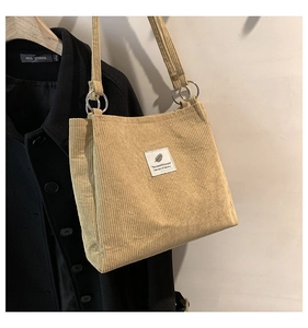 Close-up of light brown corduroy tote bag with metal ring strap and logo patch details