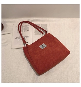 Detail of caramel corduroy tote bag texture and leaf logo label on a lifestyle magazine