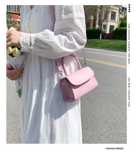 Pink mini leather crossbody bag with FASHION & BAG lettering held by a model with flowers