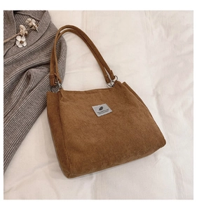 Detailed macro view of brown corduroy tote bag texture with a minimalist fabric label