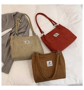 Close-up of corduroy tote bags in beige, burgundy, and caramel with feather label